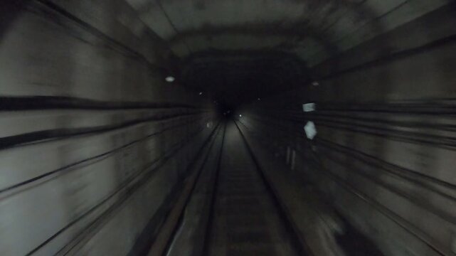Subway train moving fast at dark tunnel. Speed underground train riding in tunnel. Urban metro driving belowground. Point of view from the railway cabin. Transportation of people concept. Time lapse