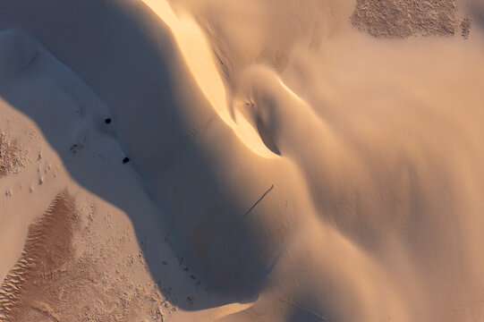 Aerial view of the golden dunes, carved by winds into rippling patterns, casting long shadows across the landscape, Da'ira, Socotra, Yemen.