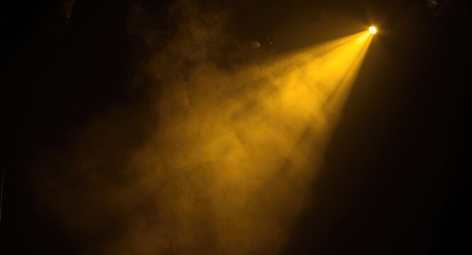 Yellow spotlight casting bright glow through smoky haze on dark theatrical stage