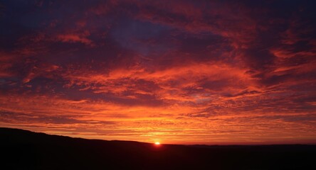 Warm crimson and vibrant orange sky during sunset with dynamic clouds