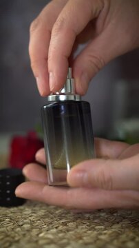 Vertical video of closing black perfume bottle and shaking to mix essential oils and alcohol. Natural homemade fragrance creation in luxury floral setting with red rose.