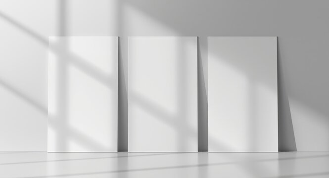 Three blank rectangular posters aligned consecutively on a gentle gray backdrop featuring shadows and copy space