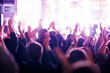 Crowd clapping at a music festival with purple stage lighting