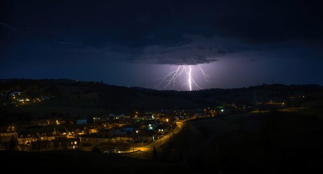 Intense lightning strike visible over a tranquil nighttime village