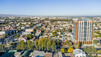 Obraz premium Aerial panorama of Bishkek, Kyrgyzstan with Soviet-era blocks, private houses, and distant smokestacks illustrating Central Asian urban growth and mixed development. 