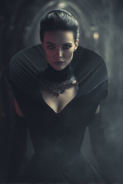 Dominant dark empress in black velvet gown representing luxury perfume concept on charcoal gray background