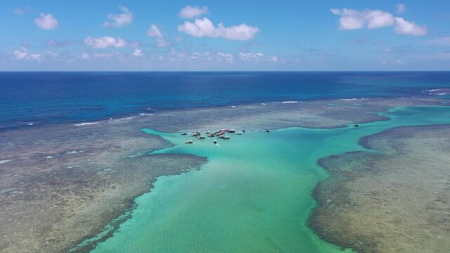 Amazing view of dozens of small boats in the natural pools among the coral reefs of Milagres beach near Maceio city, coast of Brazil 