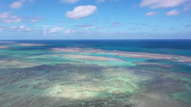 Aerial view of Rota dos Milagres beach with fantastic turquoise waters, white sand beaches, coconut trees and small boats. Patacho, Maceio city, Brazil 