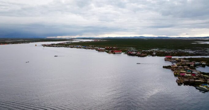 Traditional totora reed islands and homes of the Uru people on Lake Titicaca in Puno, Peru. Aerial forward, copy space