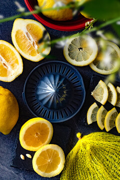 Rodajas de lim&oacute;n y preparaci&oacute;n c&iacute;trica sobre fondo oscuro.Rodajas y gajos de lim&oacute;n alrededor de un exprimidor negro con cuchillo amarillo sobre fondo oscuro. Composici&oacute;n c&iacute;trica fresca y concepto
