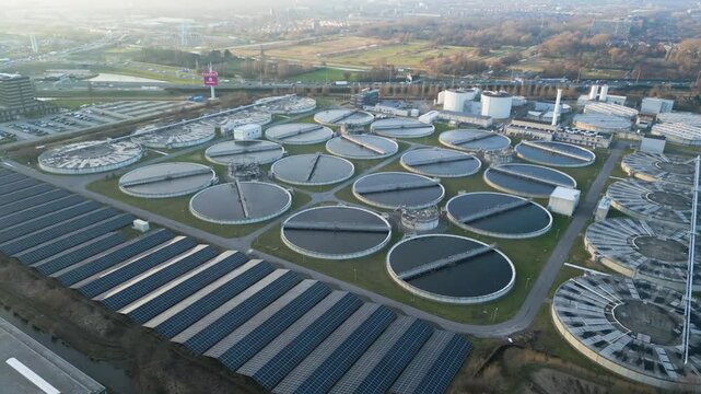 Drone shot of multiple circular clarifier tanks at a large wastewater treatment facility.