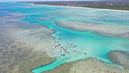 Obraz premium Fantastic aerial view of the turquoise waters of Toque beach with dozen of small boats with tourists on the natural pools formed among coral reefs in Milagres route near Maceio, Alagoas State, Brazil 