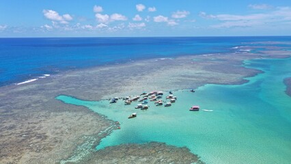 Fantastic aerial view of the turquoise waters of Toque beach with dozen of small boats with tourists on the natural pools formed among coral reefs in Milagres route near Maceio, Alagoas State, Brazil 
