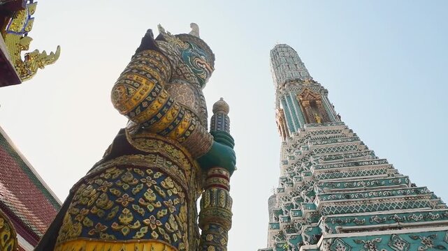 Bangkok, Thailand - 15th february, 2024: Bangkok Thailand Wat Arun yaksha guardian statue beside turquoise prang, ornate ceramic mosaic temple architecture, Thai culture heritage landmark travel