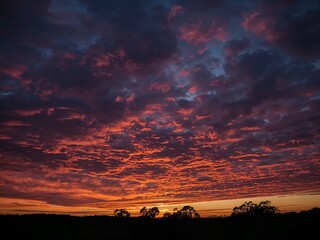 Obraz premium Fiery sunset with vibrant colors across the sky, offering a stunning and dramatic view 