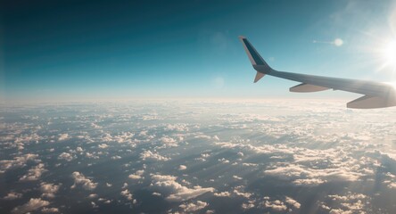 Fototapeta premium Aerial view from airplane wing flying through a blue sky with soft cloud clusters
