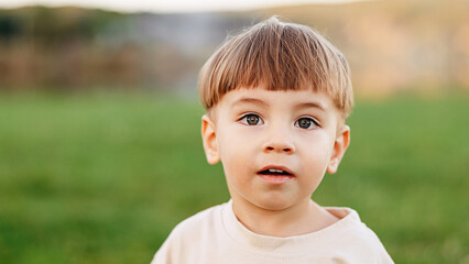 Young Boy Portrait Outdoors Looking Curious in a Green Field with Natural Light