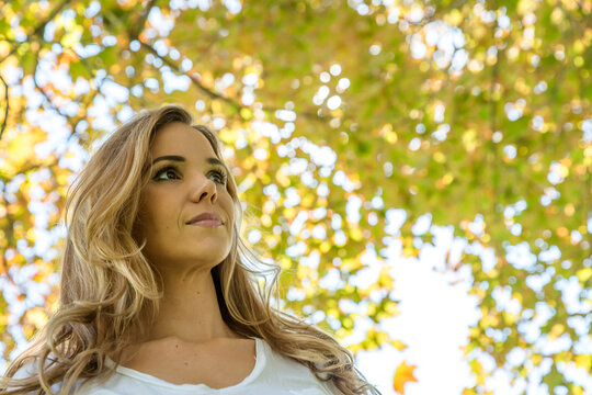 Low angle Portrait of a beautiful woman in smart casual clothing standing in a park in summer