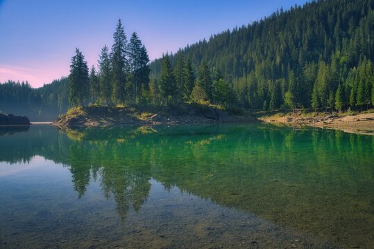View into land of a lakeshore forest landscape across Lake Cauma (Caumasee) near Flims, The Grisons, Switzerland