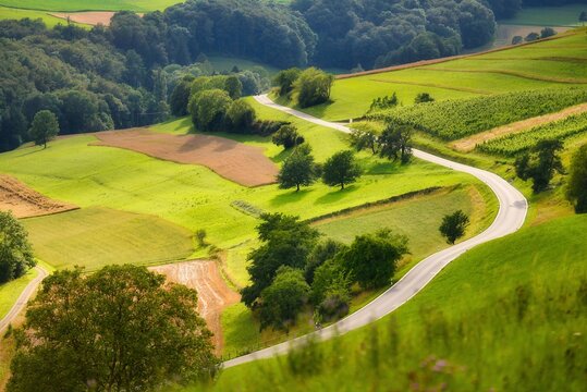 Aerial view of a winding road through a lush farmland landscape in springtime, Aargau, Switzerland