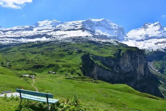Empty bench in a lush mountain landscape with snowcapped mountains in the background, Untere Balm, Klausen Pass, Switzerland