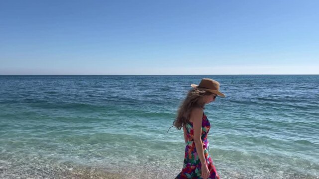 C&aacute;mara lenta de mujer caminando por la orilla con el viento moviendo su vestido