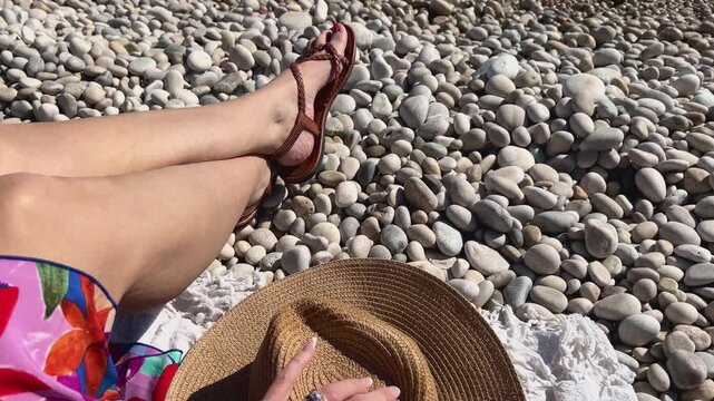 Detalle mano tocando sombrero en toalla con mar de fondo