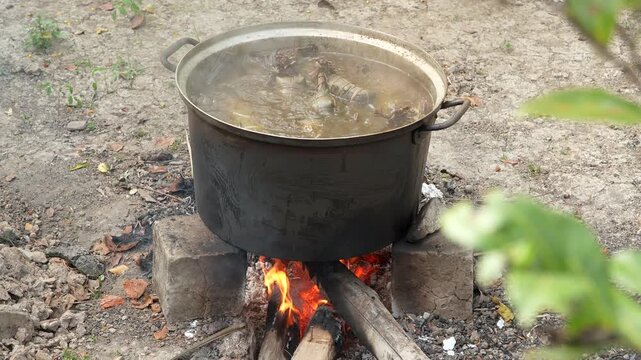 Boiling traditional Banh Tet in open pot over wood fire for Tet Holiday
