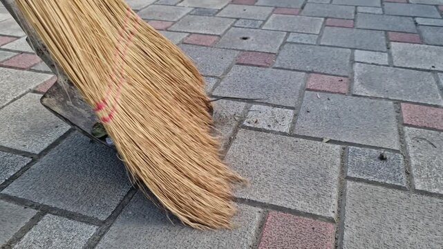A broom sweeps trash into a dustpan