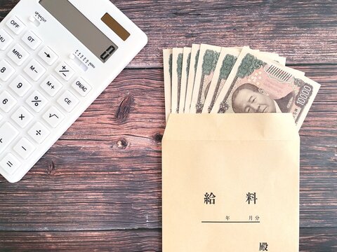 Japanese Salary Envelope with Yen Banknotes and Calculator on Wooden Table