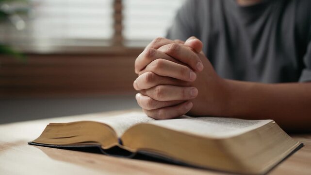 Hands clasped prayer with Holy Bible for Christian faith, spirituality, worship, devotion, hope, and religious belief, prayer time in church, trust in God, and spiritual guidance.