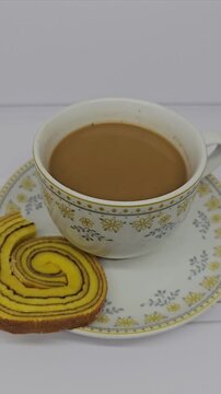 A cup of coffee with milk and lapis legit cake, one of Indonesia's traditional cakes,  isolated on white background, enjoying coffee in the morning.