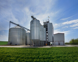 metal silos for storage, grain elevator complex for receiving, cleaning, drying and long-term storage, norias for lifting grain and a working tower © pavlobaliukh