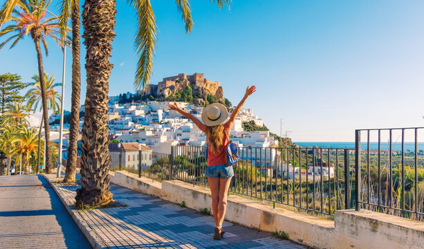 Happy traveler female with bag and hat enjoying castle and white houses in Salobre&ntilde;a, Spain, Granada province