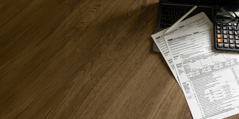 Financial paperwork tax form with calculator on workspace, accounting filing, income documentation, and corporate compliance process.