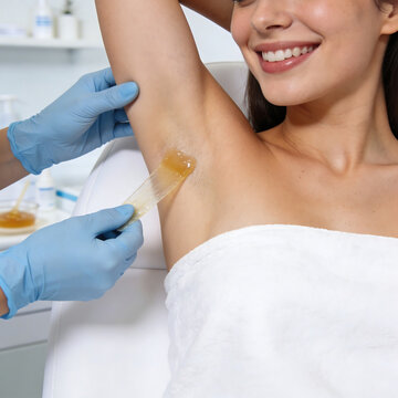 Professional armpit sugaring procedure in a bright medical spa. Aesthetician in blue gloves applying sugar paste