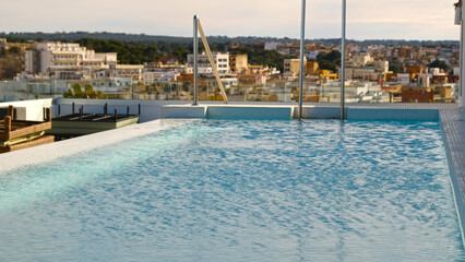 Rooftop pool with calm turquoise water and urban skyline view. For travel, real estate, hospitality and premium lifestyle campaigns.