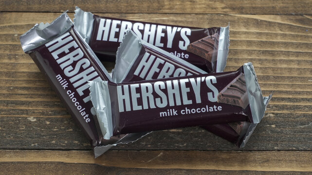 NORWALK, CT, USA - FEBRUARY 24, 2026: Four Hershey's milk chocolate bars are resting on a wooden table. The wrappers are silver and dark brown. This setup invites a moment of enjoyment and taste.