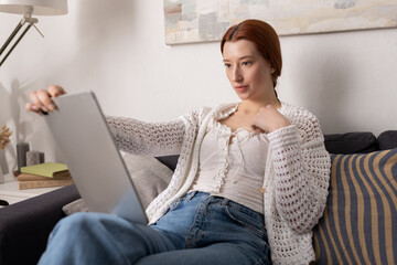 Fototapeta premium Red-haired woman enjoys a cozy afternoon in her modern apartment