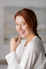 Fototapeta premium Young woman with red hair enjoys a peaceful moment at home in her stylish apartment