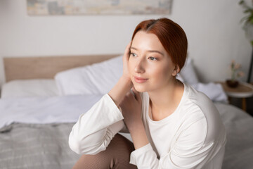 Naklejka premium Young woman with red hair enjoys a peaceful moment in her cozy modern apartment
