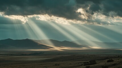 Dramatic Sunlight Breaking Through Clouds Over Open Field and Mountains in a Vast Rural Landscape