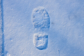 Close-up of a single human boot footprint in fresh white snow during winter in Wisconsin. Detailed shoe tread mark on a cold snowy surface.