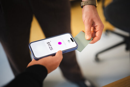 A person uses a mobile device to make a contactless payment for a purchase of seventeen dollars and twenty-five cents.