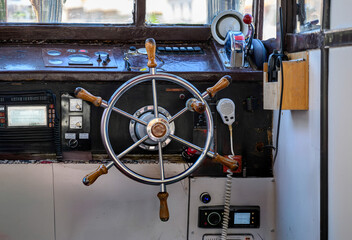 Vue rapprochée d’une timonerie de bateau avec un gouvernail de navire brillant, des instruments de navigation et des commandes radio. © William Vallée
