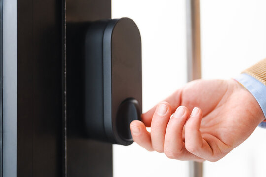 A person's hand is shown interacting with a modern smart lock on a door, suggesting access and security.