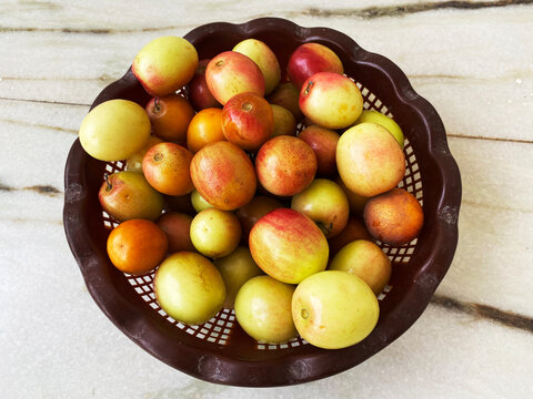 Fresh, ripe Indian jujube (ber) fruits with reddish-yellow skin arranged in a brown perforated basket, showcasing natural shine and farm-fresh appeal.