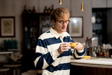 Young man enjoys a warm drink at a stylish cafe in a lively afternoon setting