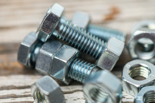 Metal M8 bolts and nuts on wooden table close-up