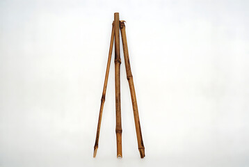 Bamboo sticks set with brown color and wooden texture arranged together in a tripod formation featuring group, arrangement, natural with material and organic elements for earthy, rustic projects,